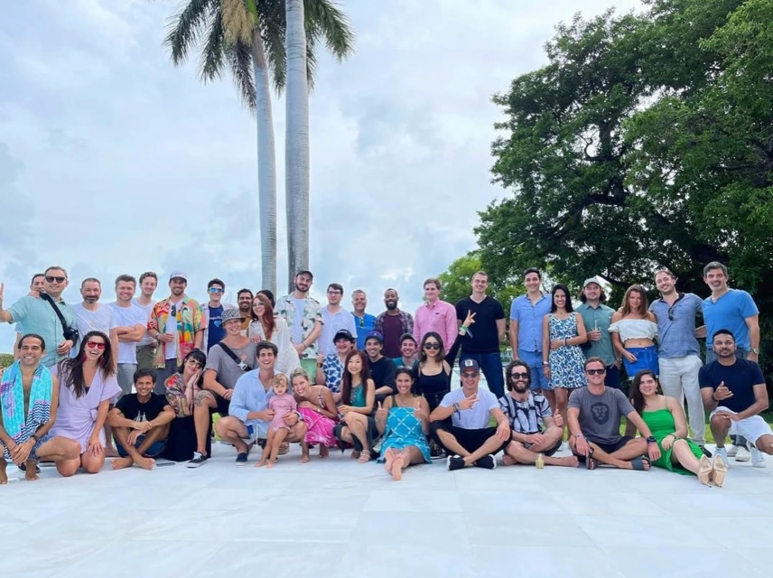 A big group photo under palm trees